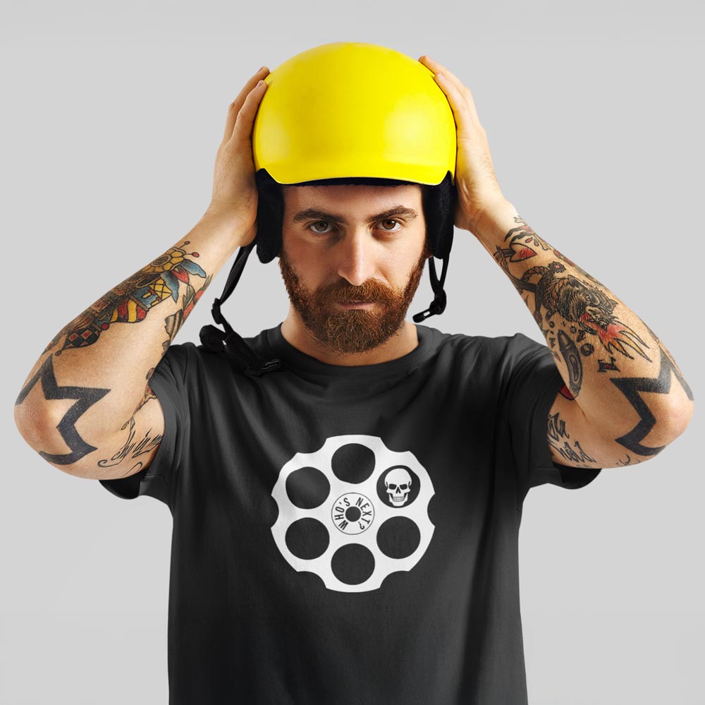 Muž v tričku s motivem revolveru a napisem Who's Next? – Organická bavlna Stanley/Stella. Fleekfox. Barva černá