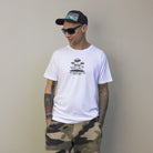 Muž v bílém tričku značky Fleekfox. Na tričku nápis "Mushroom Meadow. Nature's wonder"