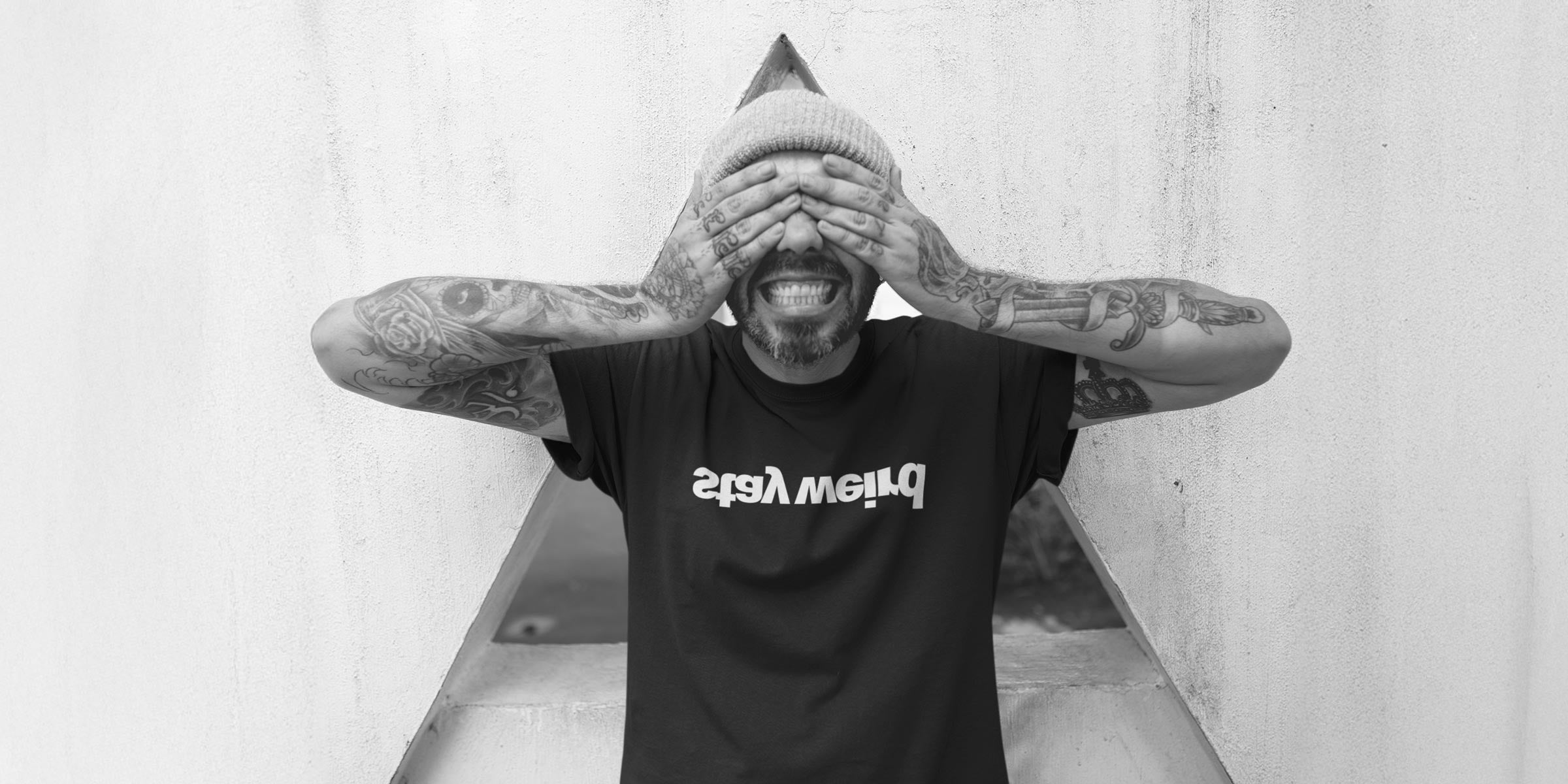 Muž v černém tričku z organické bavlny.  Nápis STAY WEIRD. Fleekfox